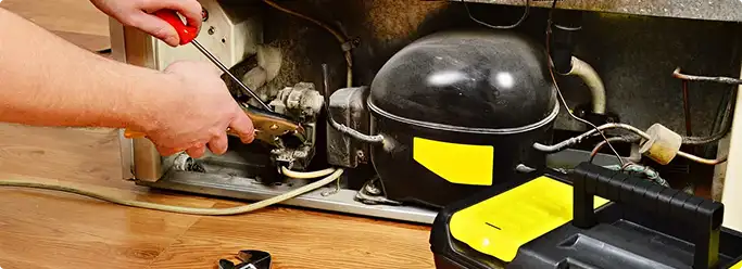 Refrigerator repair technician fixing the compressor and wiring in Orange, NJ