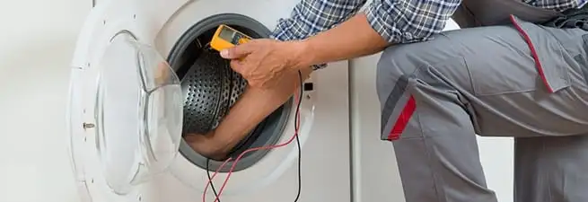 Dryer repair technician inspecting and repairing a clothes dryer in Newark, NJ
