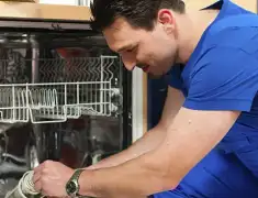 Dishwasher repair technician inspecting and servicing an open dishwasher in Newark, NJ