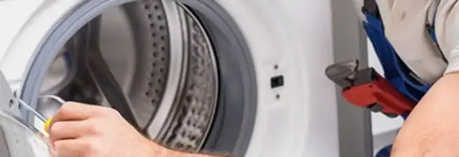 Appliance technician repairing a clothes dryer drum and internal parts in Newark, NJ