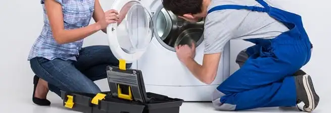 Washer repair technician inspecting a front-load washing machine with tools in Newark, NJ