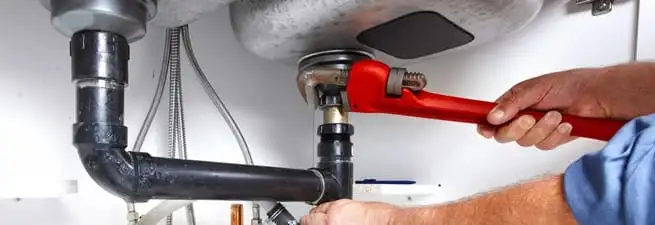 Garbage disposal repair technician tightening the sink drain and disposal connection in Newark, NJ