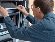 Appliance repair technician replacing a microwave vent filter in Newark, NJ