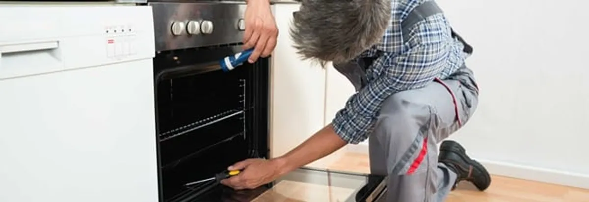 Oven repair technician inspecting and servicing an electric oven in Newark, NJ