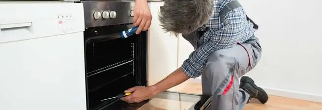 Oven repair technician inspecting and servicing an electric oven in Newark, NJ
