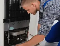 Refrigerator repair technician servicing the compressor and condenser area in Newark, NJ