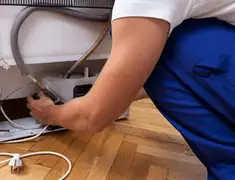 Appliance repair technician fixing refrigerator water line and connections in Newark, NJ
