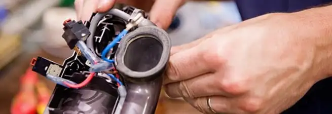 Vacuum repair technician reconnecting wiring and components in Newark, NJ