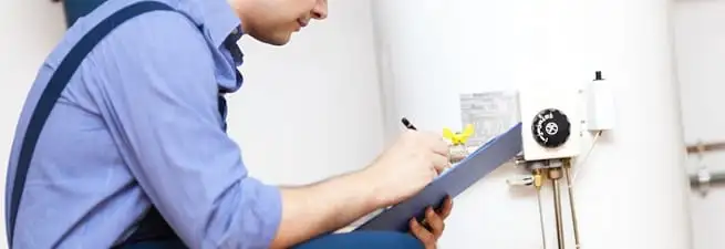 Water heater repair technician inspecting the unit and recording service notes in Newark, NJ