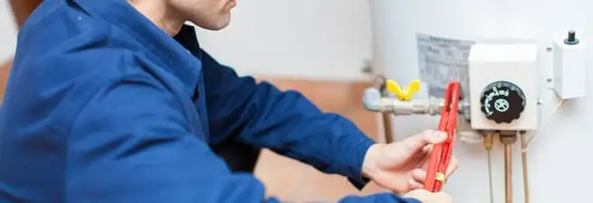 Water heater repair technician adjusting the temperature control and gas valve in Newark, NJ